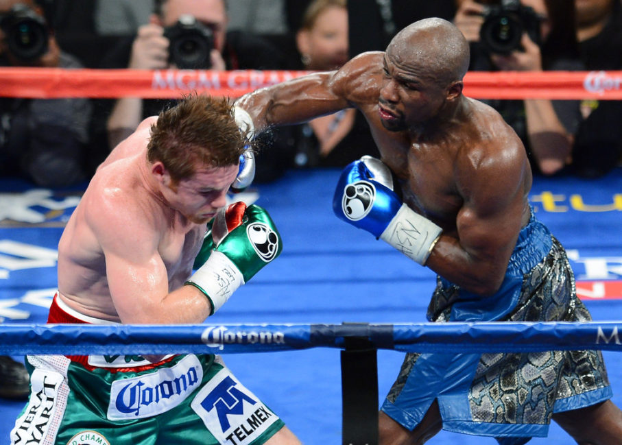 Floyd Mayweather Jr. (R) hits Canelo Alvarez in the fifth round of their WBC/WBA 154-pound title fight